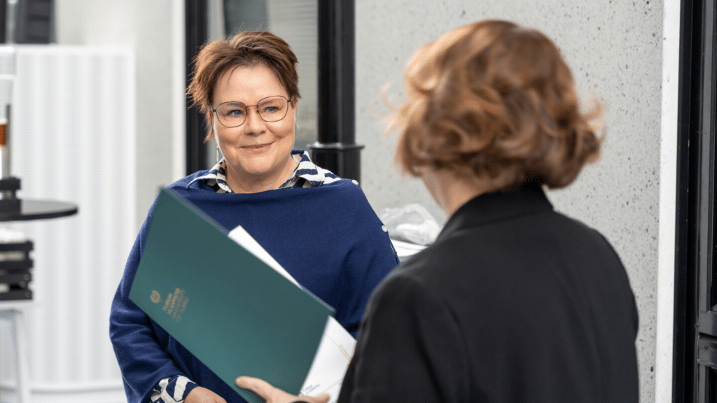 Benita Heiskanen lähikuvassa; ikkunasta näkyy Turun yliopiston alakampus.